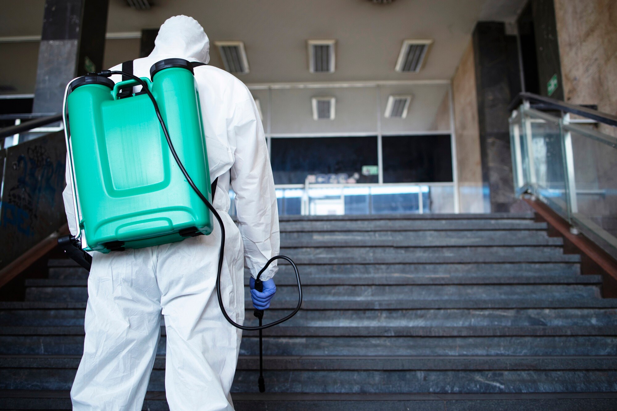 unrecognizable-person-white-chemical-protection-suit-with-reservoir-disinfecting-public-corridor-stop-spreading-highly-contagious-corona-virus_342744-867